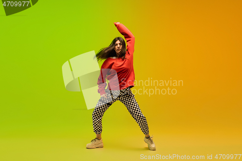 Image of Stylish sportive girl dancing hip-hop in stylish clothes on colorful background at dance hall in neon light. Youth culture, movement, style and fashion, action.