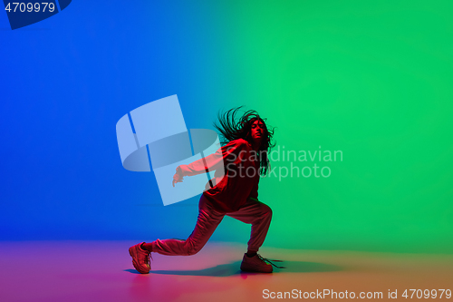 Image of Stylish sportive girl dancing hip-hop in stylish clothes on colorful background at dance hall in neon light. Youth culture, movement, style and fashion, action.