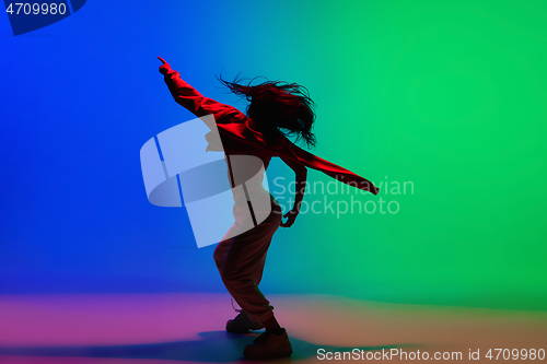 Image of Stylish sportive girl dancing hip-hop in stylish clothes on colorful background at dance hall in neon light. Youth culture, movement, style and fashion, action.