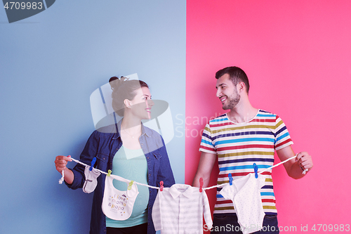 Image of young couple holding baby bodysuits