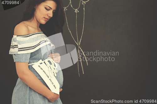 Image of Portrait of pregnant woman in front of black chalkboard