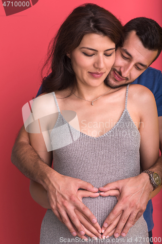 Image of pregnant  couple showing heart with their hands