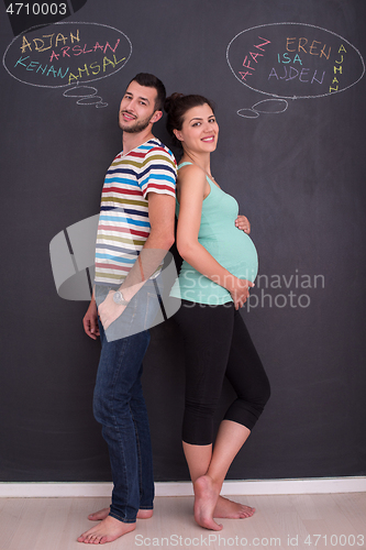 Image of pregnant couple writing on a black chalkboard