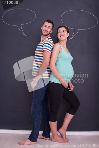 Image of pregnant couple writing on a black chalkboard