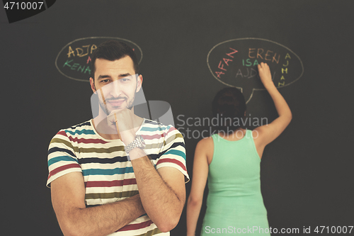 Image of pregnant couple writing on a black chalkboard