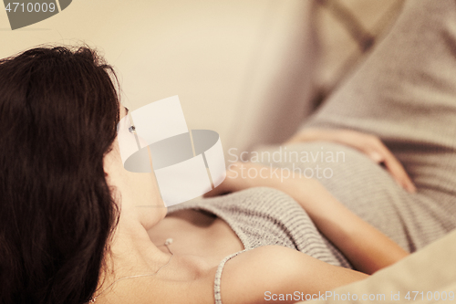 Image of pregnant woman sitting on sofa at home