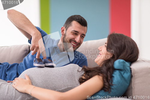 Image of young pregnant couple relaxing on sofa