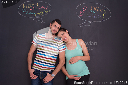 Image of pregnant couple writing on a black chalkboard