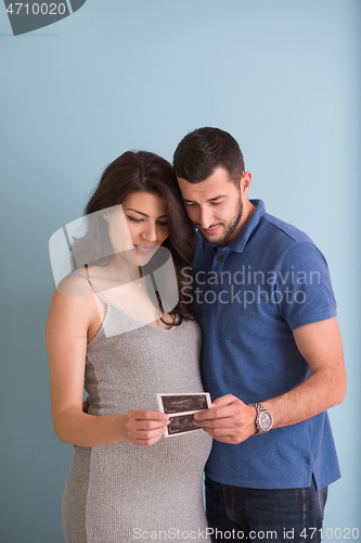 Image of couple looking ultrasound picture isolated on blue background