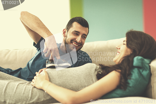 Image of young pregnant couple relaxing on sofa