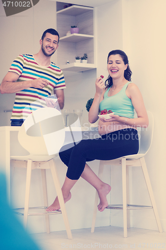 Image of couple eating fruit strawberries at kitchen