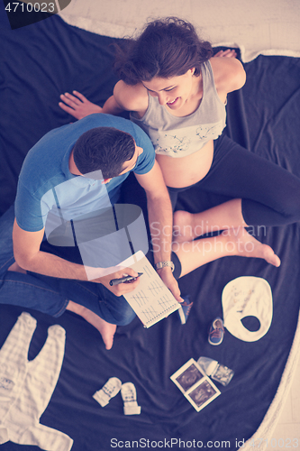 Image of top view of couple checking a list of things for their unborn ba