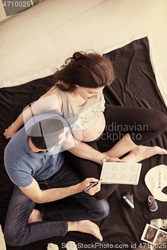 Image of top view of couple checking a list of things for their unborn ba