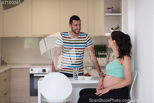 Image of couple eating fruit strawberries at kitchen