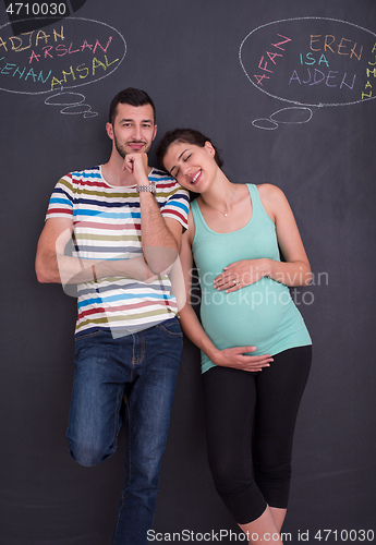 Image of pregnant couple writing on a black chalkboard