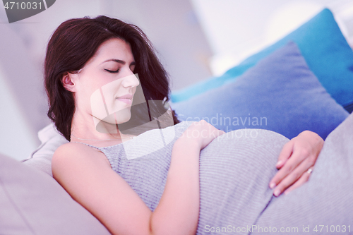 Image of pregnant woman sitting on sofa at home