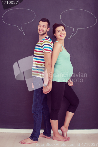 Image of pregnant couple writing on a black chalkboard