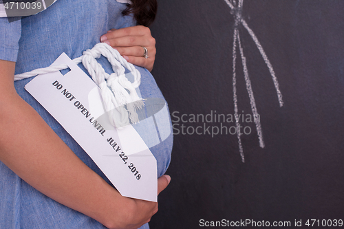 Image of Portrait of pregnant woman in front of black chalkboard