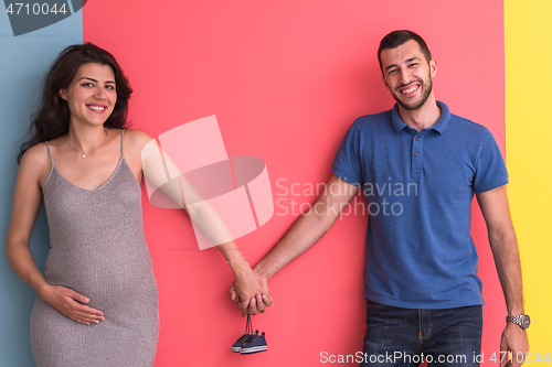 Image of young happy couple holding newborn baby shoes