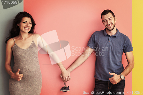 Image of young happy couple holding newborn baby shoes