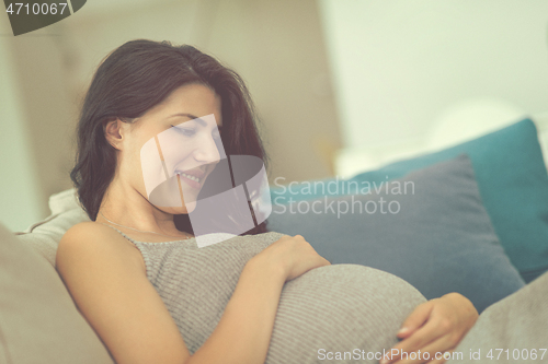 Image of pregnant woman sitting on sofa at home