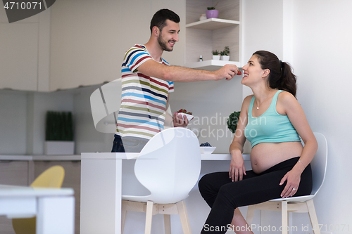 Image of couple eating fruit strawberries at kitchen