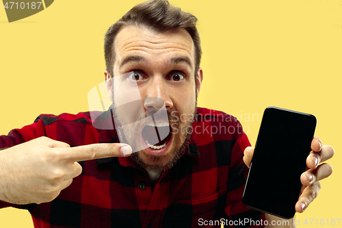 Image of Half-length close up portrait of young man on yellow background.