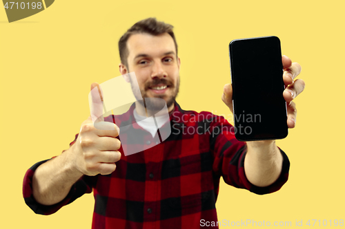 Image of Half-length close up portrait of young man on yellow background.