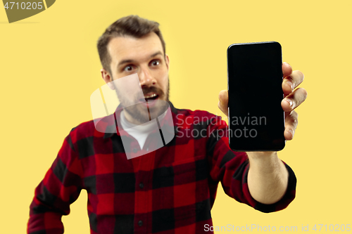 Image of Half-length close up portrait of young man on yellow background.