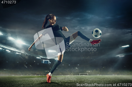 Image of Female soccer player kicking ball at the stadium