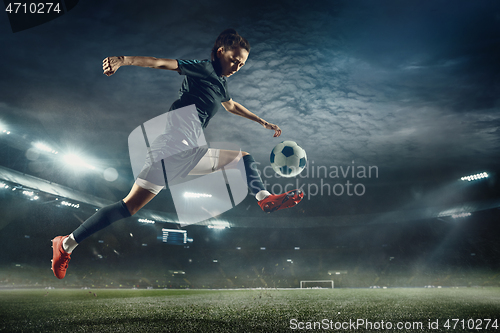 Image of Female soccer player kicking ball at the stadium