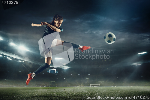 Image of Female soccer player kicking ball at the stadium