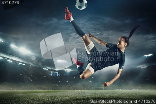 Image of Female soccer player kicking ball at the stadium