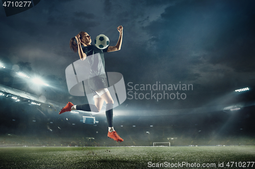 Image of Female soccer player kicking ball at the stadium