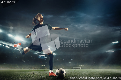 Image of Female soccer player kicking ball at the stadium