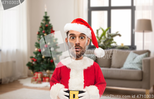 Image of surprised man in santa costume over christmas tree