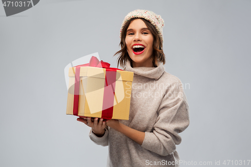 Image of young woman in knitted winter hat holding gift box