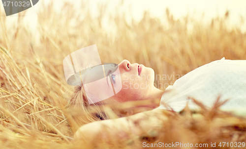 Image of young woman lying on cereal field and dreaming