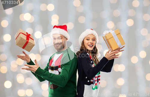 Image of happy couple in christmas sweaters with gifts