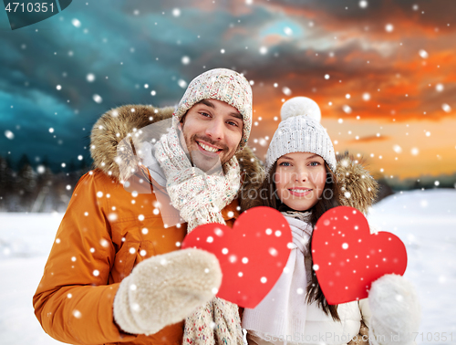 Image of happy couple with red hearts over winter landscape