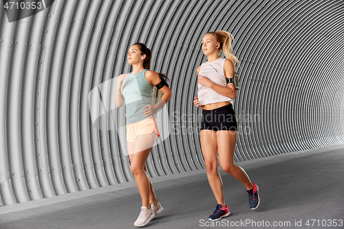 Image of young women with earphones and smartphones running