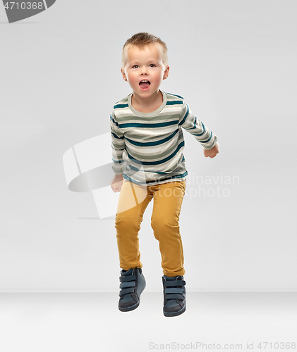 Image of portrait of little boy in striped shirt jumping