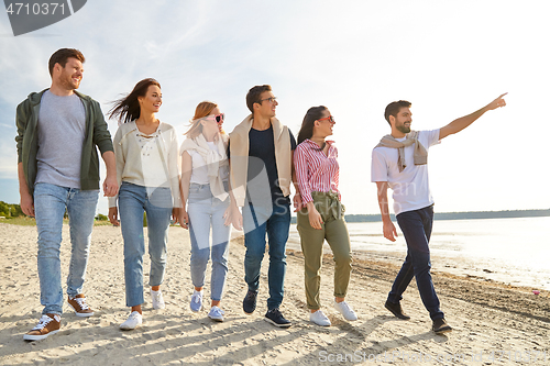 Image of happy friends walking along summer beach