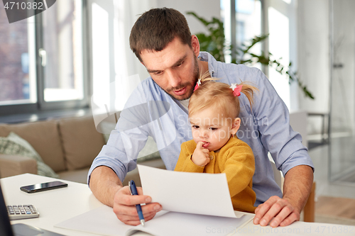 Image of working father with baby daughter at home office