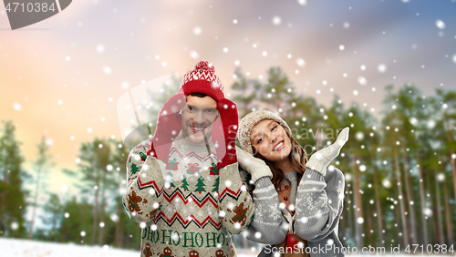 Image of happy couple in ugly christmas sweaters in winter