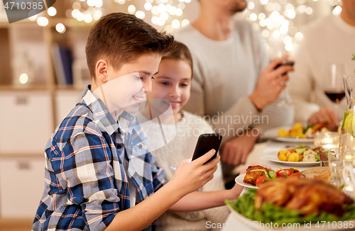 Image of boy with sister using smartphone at family dinner