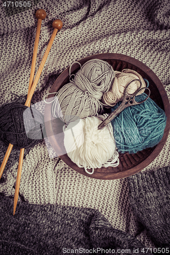 Image of Home life - Knitting concept, knitting needles with blanket, scissors and yarn in wooden bowl