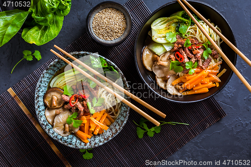 Image of Asia style ramen soup with udon noodle, beef, shiitake, pak choi cabbage and carrots