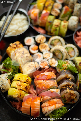 Image of Assorted sushi set served on dark dark background. Top view of seafood, various maki rolls