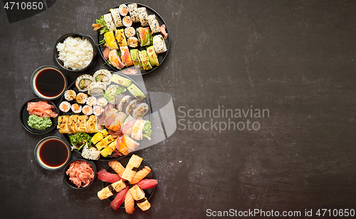 Image of Assorted sushi set served on dark dark background. Top view of seafood, various maki rolls